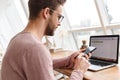 Image of young man working on laptop and using cellphone in cafe Royalty Free Stock Photo