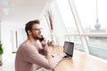 Image of young man working on laptop and using cellphone in cafe Royalty Free Stock Photo