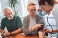 Young medic taking blood pressure during home visit Royalty Free Stock Photo