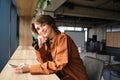 Image of young modern woman, employee in office, sitting at co-working space, working, using mobile phone, looking happy Royalty Free Stock Photo