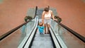 Photo of young mother holding her little son by hand while riding on the escalator at shopping mall Royalty Free Stock Photo