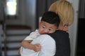 Young mother trying to calm her crying baby son at home. Royalty Free Stock Photo