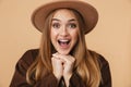 Image of young optimistic girl wearing hat and coat laughing at camera