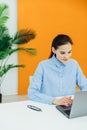 Image of young pleased happy cheerful cute beautiful business woman sit indoors in office using laptop Royalty Free Stock Photo