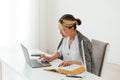 Image of young pleased happy cheerful cute beautiful business woman sit indoors in office using laptop computer Royalty Free Stock Photo