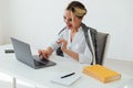 Image of young pleased happy cheerful cute beautiful business woman sit indoors in office using laptop computer Royalty Free Stock Photo