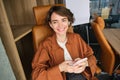 Image of young professional entrepreneur, woman in an office, sitting in chair in an office, using mobile phone Royalty Free Stock Photo