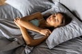 Young smiling pretty lady lies in bed indoors. Eyes closed Royalty Free Stock Photo