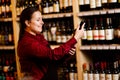 Image of young woman with bottle in her hands in wine shop