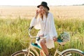 Image of young woman holding flowers and riding bicycle in countryside Royalty Free Stock Photo