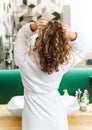 Image of young woman in housecoat standing in bathroom after shower