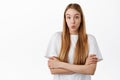 Image of young woman in t-shirt, cross arms on chest and looks surprised, say wow, stare with curious and excited face