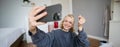 Image of young woman, vlogger taking selfie in her room, talking to her followers during online live stream, using Royalty Free Stock Photo