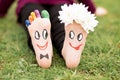 Images of lovely groom and bride just married painted in bright colors on feet of child outdoor at summer.