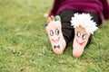 Images of lovely groom and bride just married painted in bright colors on feet of child outdoor at summer.