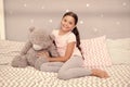 Imagination and development. Happy child cuddle teddy bear in bed. Little girl smile with childhood playmate. Enjoying