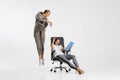 Two women at office isolated over white background. Imagination. Personal assistant pouring coffee on boss head.