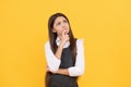 Imaginative girl child in school uniform keep thinking yellow background, imagination