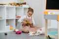 Imaginative little girl playing with a doll, trying on different clothes.