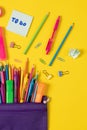 Imagine of colorful pens, markers, crayons in pencil box on yellow background