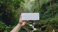 hand holding blank white card against rainforest background
