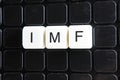 IMF title text word crossword. Alphabet letter blocks game texture background. White alphabetical letters on black Royalty Free Stock Photo