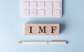 IMF on wooden cubes with pen and calculator, financial concept