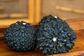 Three black truffles (Tuber melanosporum) are displayed on a wooden surface Royalty Free Stock Photo