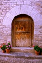 Semicircular entrance to the stone house, wooden antique door, flowers in pots. Royalty Free Stock Photo