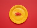 Imitation of a red crab claw in a yellow plate on a red background. Flat lay Royalty Free Stock Photo