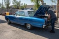 immense blue classic American car Dodge Polara. The trunk is open and the owner is loading