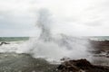 Immense waves hitting a large rock at the edge of the beach. Force of nature