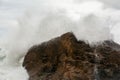 Immense waves hitting a large rock at the edge of the beach. Force of nature