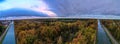 Autumn Tapestry: Aerial View of River or Canal Flowing Through Colorful Woods Under a Dramatic Cloudy Sky