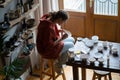 Immersive in process artisan woman sitting in ceramic studio working on creating unique tableware