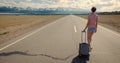 Immigration concept. Downshifting. Alone woman with suitcase walk on empty road to wild nature