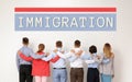 Immigration concept. Group of people hugging each other near light wall Royalty Free Stock Photo