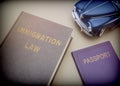 Immigration law book next to a passport and blue miniature vehicle