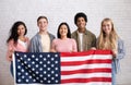 Immigration, relocation and study abroad. Cheerful young international students hold USA flag