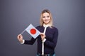 Immigration and the study of foreign languages, concept. A young smiling woman with a Japan flag in her hand.