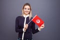 Immigration and the study of foreign languages, concept. A young smiling woman with a Tunisia flag in her hand.