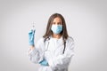 Immunization concept. Senior doctor woman in medical mask holding syringe with vaccine dose ready to make injection shot Royalty Free Stock Photo