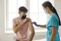Nurse disinfects skin on young man& x27;s arm before giving him Covid-19 or flu vaccine Royalty Free Stock Photo