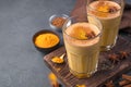 Immuno-supportive drink with milk, turmeric, coffee and cinnamon on a dark background.