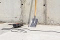 impact drill with a flat chisel on a monolithic ceiling, a shovel stands against the wall