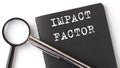 IMPACT FACTOR - business concept, magnifier with white text message on the black notebook Royalty Free Stock Photo