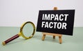 Impact Factor text on paper card with magnifying glass on green background Royalty Free Stock Photo