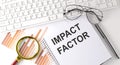 IMPACT FACTOR text written on a notebook with keyboard, chart,and glasses Royalty Free Stock Photo