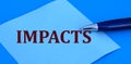 IMPACTS word written with a pen on blue paper on a blue background