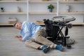 Impaired senior man lying on floor after his wheelchair tripped over indoors